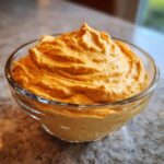 A bowl of creamy pumpkin fluff, a quick and easy dessert, sits on a countertop.