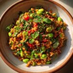 A vibrant bowl of crispy rice salad with edamame, herbs, and sesame seeds.