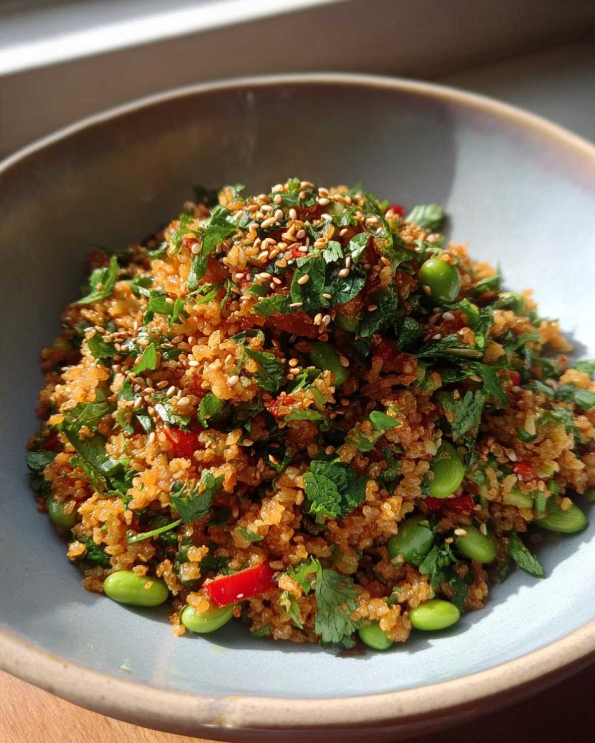 A vibrant bowl of crispy rice salad with herbs, edamame, and sesame seeds.