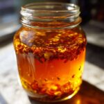 Close-up of a glass jar filled with homemade fire cider recipe ingredients steeping in liquid.