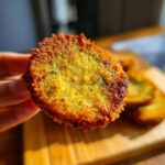 Close-up of a crispy fried green tomato slice, showcasing its golden-brown crust and green interior.