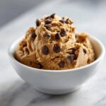A white bowl filled with delicious high protein cookie dough and chocolate chips.