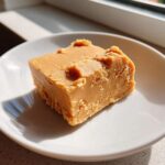 A square slice of peanut butter fudge on a white plate, showcasing the texture of the peanut butter fudge recipe.