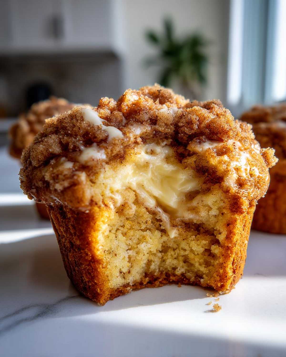 A pumpkin cheesecake muffin with a bite taken out, revealing the creamy cheesecake filling and crumb topping.