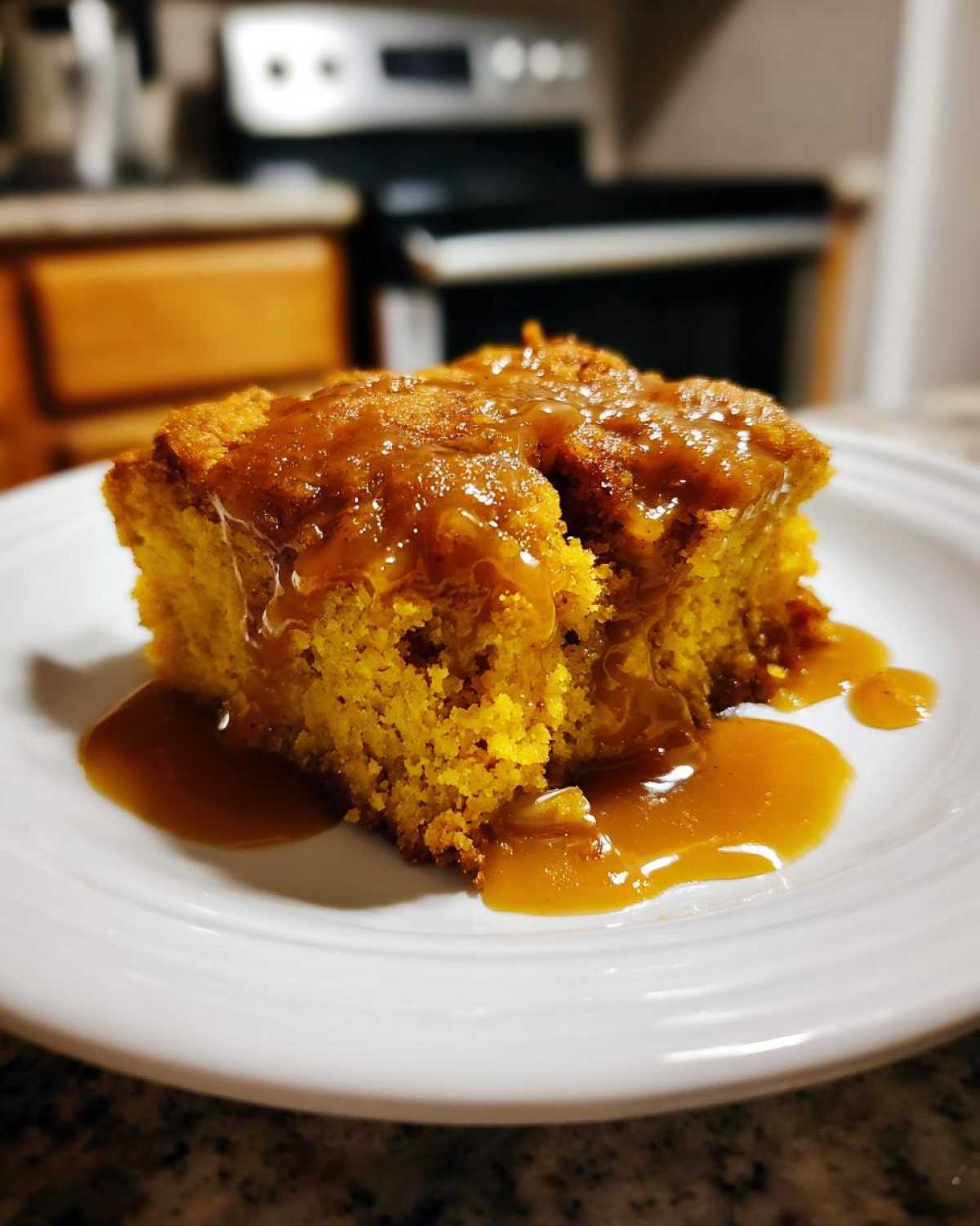 A slice of pumpkin cobbler on a white plate, drizzled with caramel sauce. Delicious pumpkin cobbler dessert.