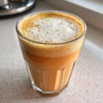A glass filled with a creamy pumpkin cold foam drink, showcasing its layered texture and rich color.