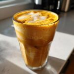 A refreshing pumpkin cream cold brew in a glass with ice, showcasing its creamy texture and vibrant color.
