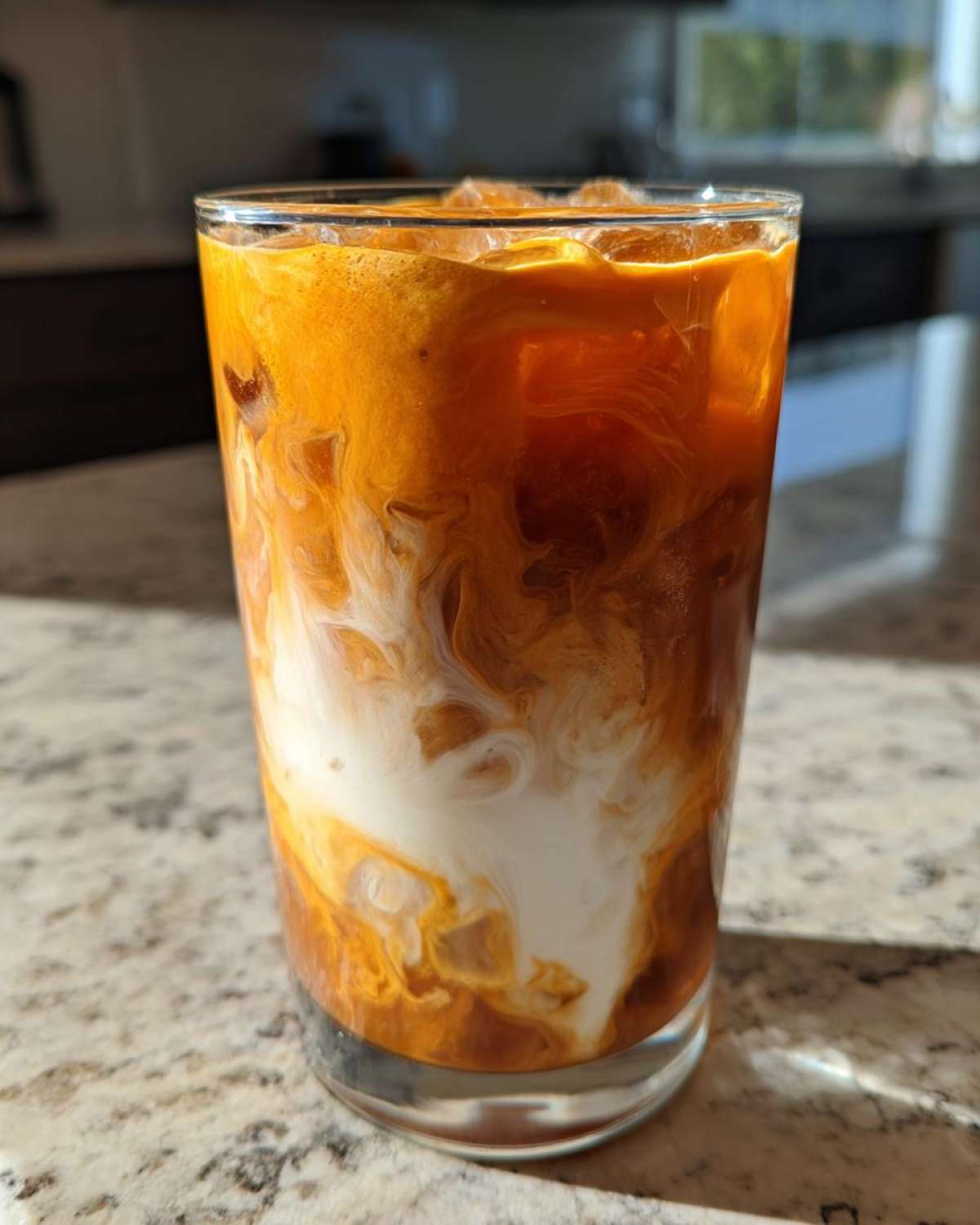 A refreshing glass of pumpkin cream cold brew with ice and a creamy swirl. Perfect for a fall treat.
