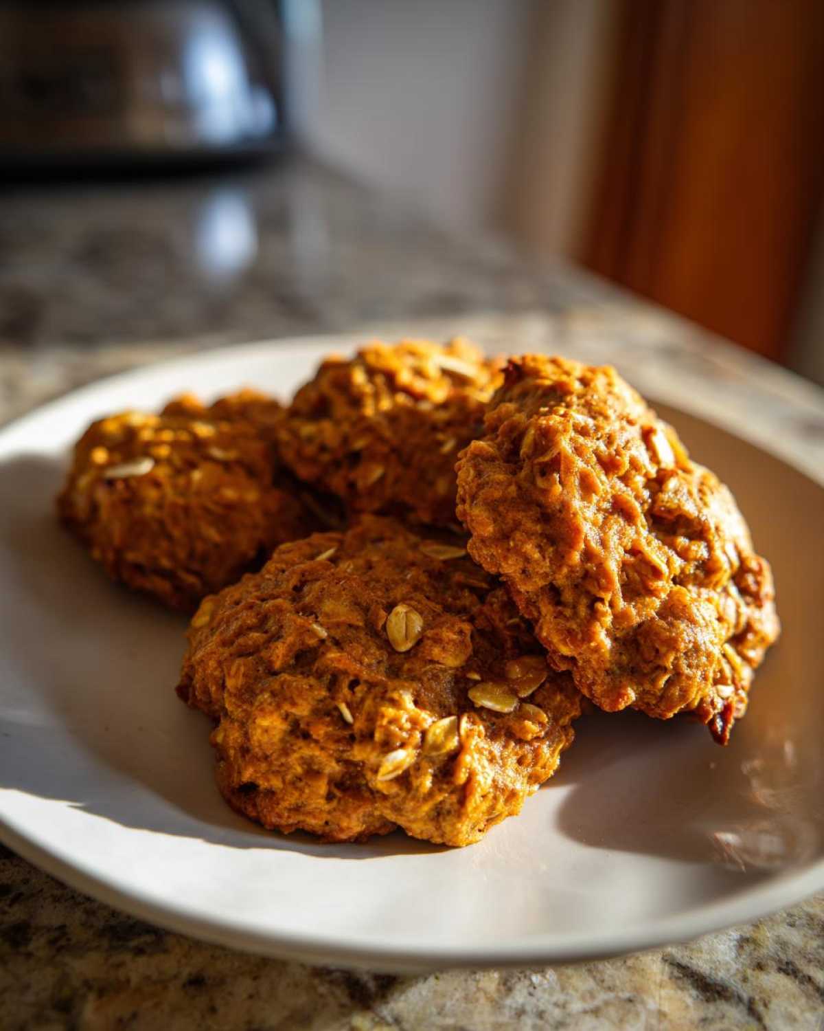 A plate of freshly baked pumpkin oatmeal cookies, golden brown and ready to enjoy.