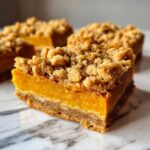 Close-up of pumpkin pie bars with a crumbly topping, showcasing the layers and texture.