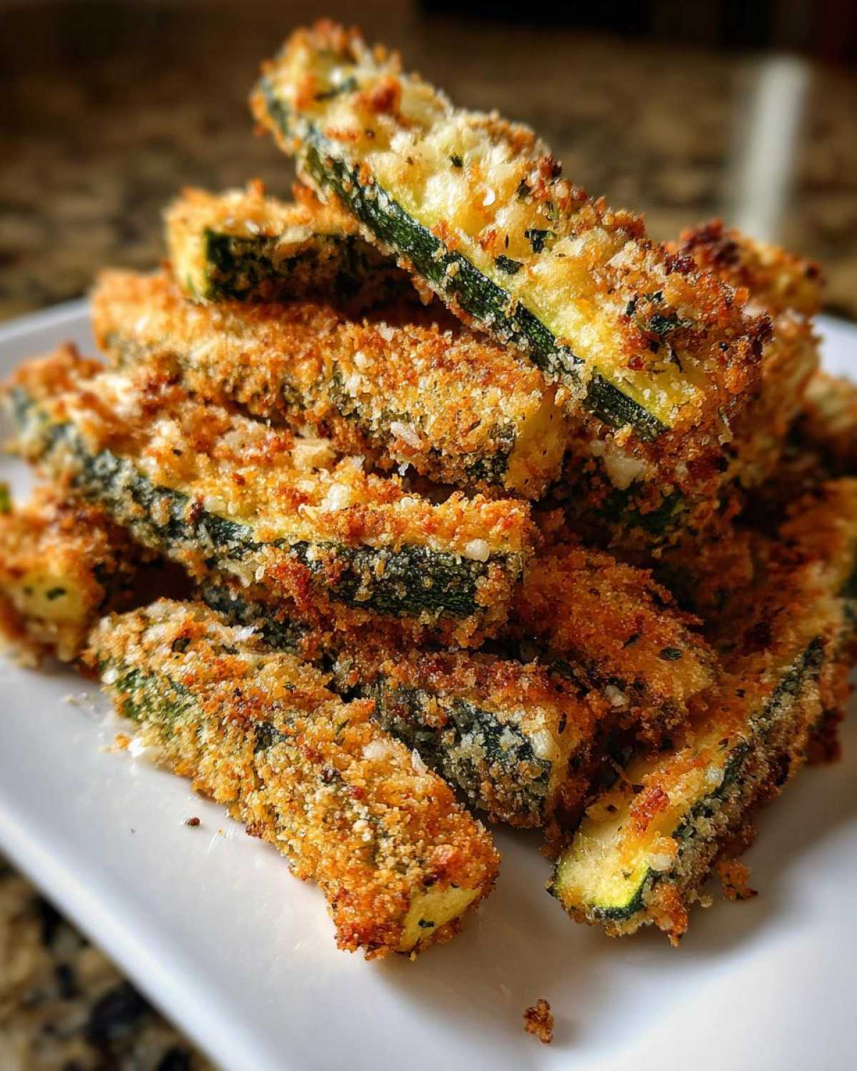 A stack of crispy Air Fryer Garlic Parmesan Zucchini Fries on a white plate.