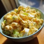 Close-up of a bowl of Amish macaroni salad with elbow pasta, celery, and hard-boiled eggs.