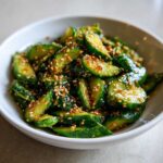 A bowl of vibrant Asian cucumber salad, featuring sliced cucumbers and sesame seeds.