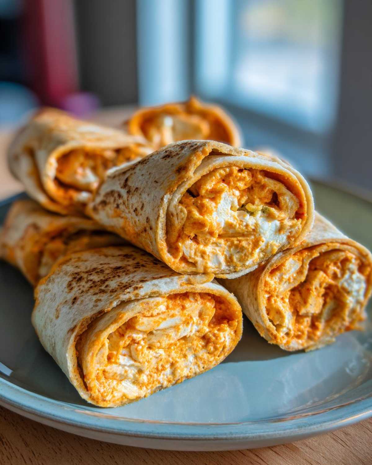 A stack of tasty Buffalo chicken pinwheels on a blue plate, ready to eat.