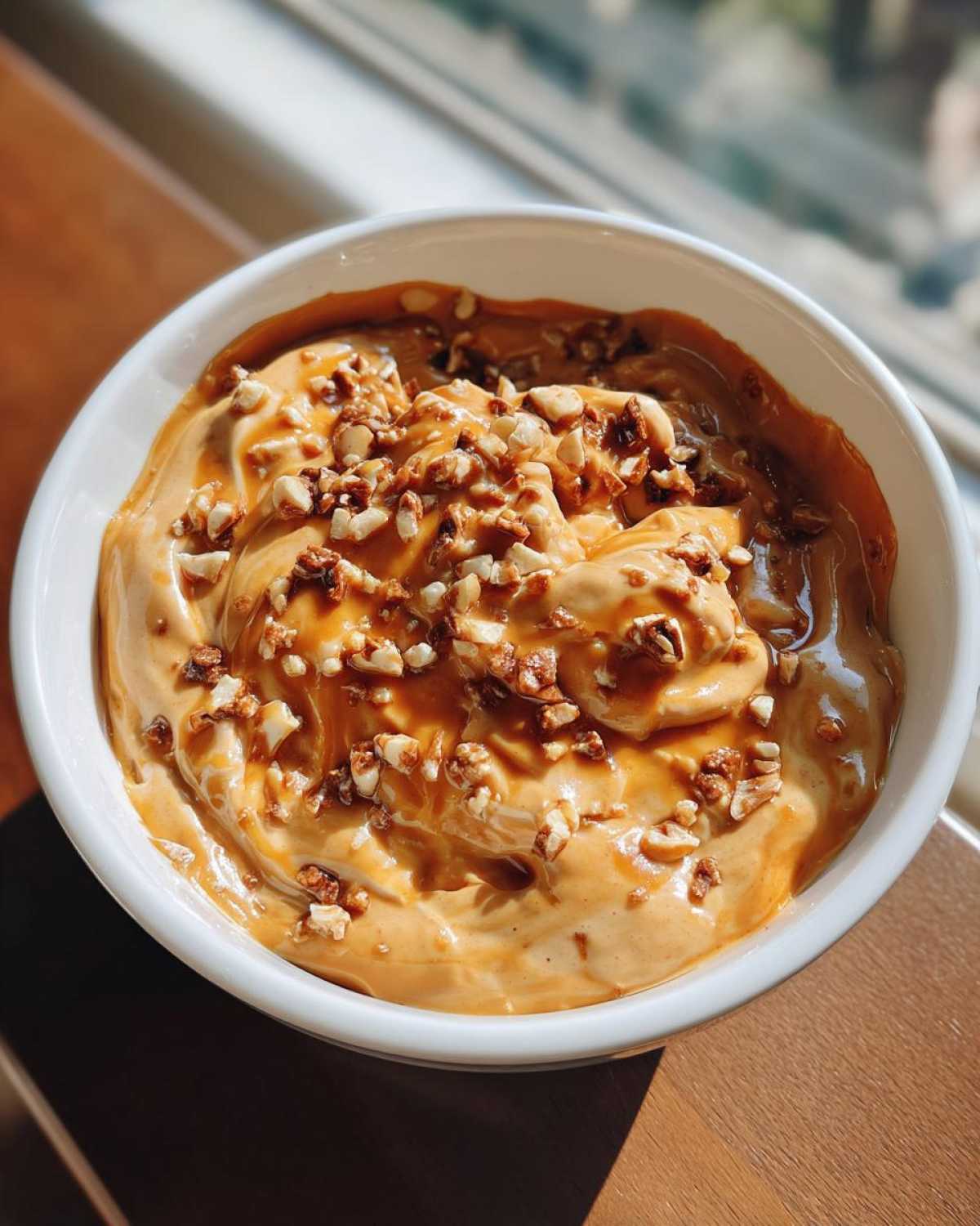 A bowl of creamy caramel apple dip, topped with chopped nuts, ready to be served.