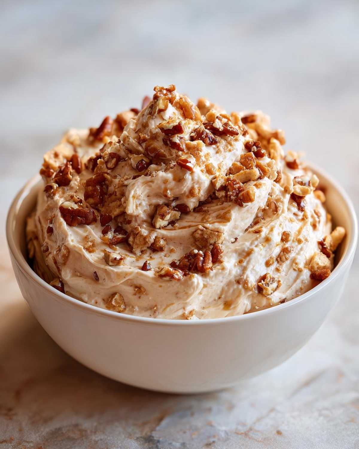 A bowl of creamy caramel apple dip, topped with chopped nuts, ready to be served.
