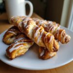 Close-up of glazed cinnamon twists on a white plate, ready to eat.