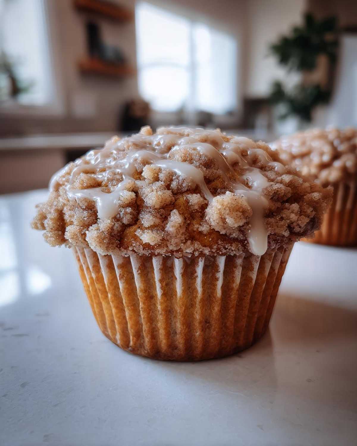 Close-up of a coffee cake muffin with a crumble topping and glaze drizzle. Perfect coffee cake muffins.