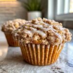 Close-up of a coffee cake muffin with a crumb topping and icing drizzle. Delicious coffee cake muffins!