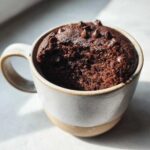 A delicious Cottage Cheese Microwave Brownie in a mug, topped with chocolate chips.