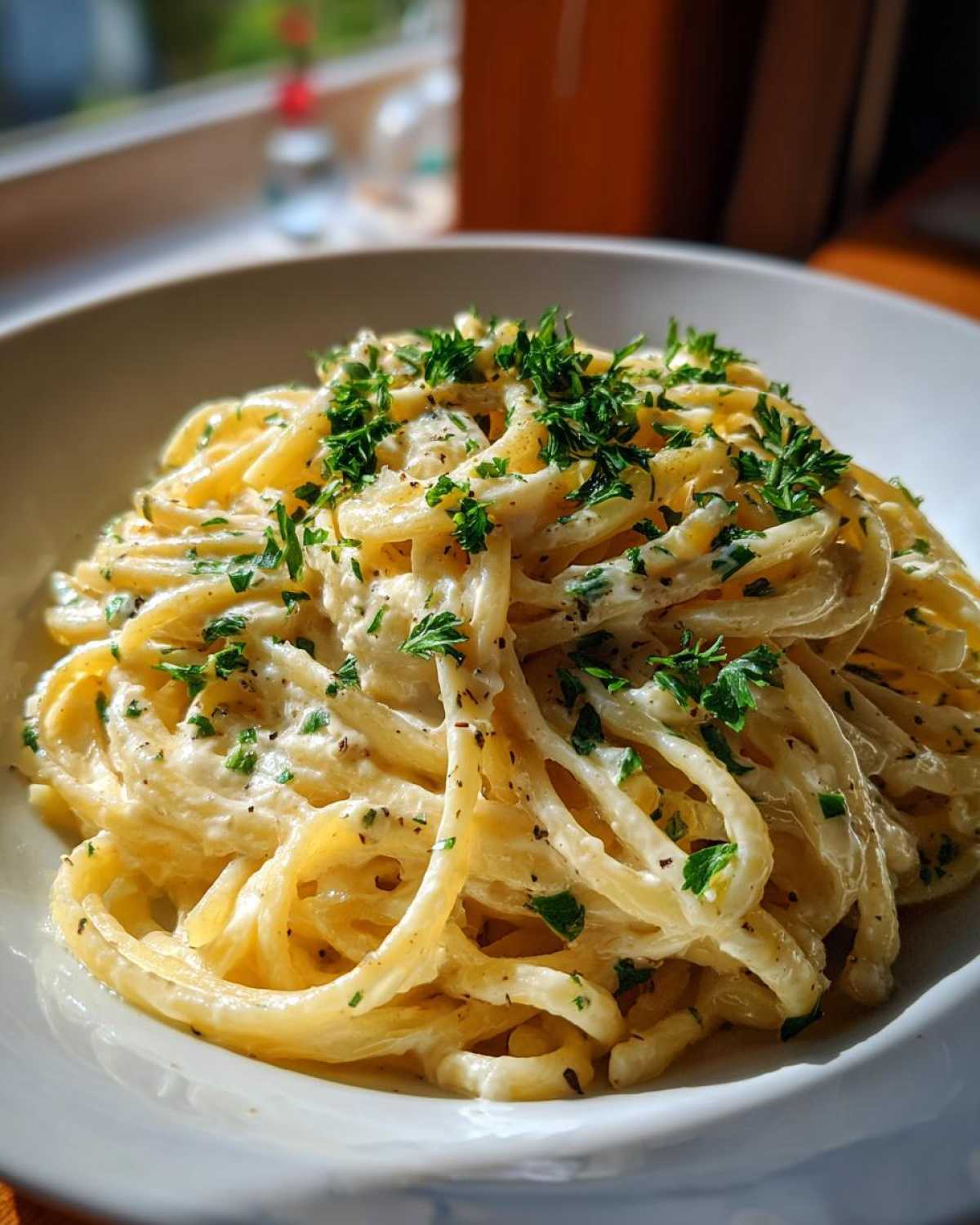 A serving of Creamy Lemon Pasta in a white bowl, garnished with fresh parsley.