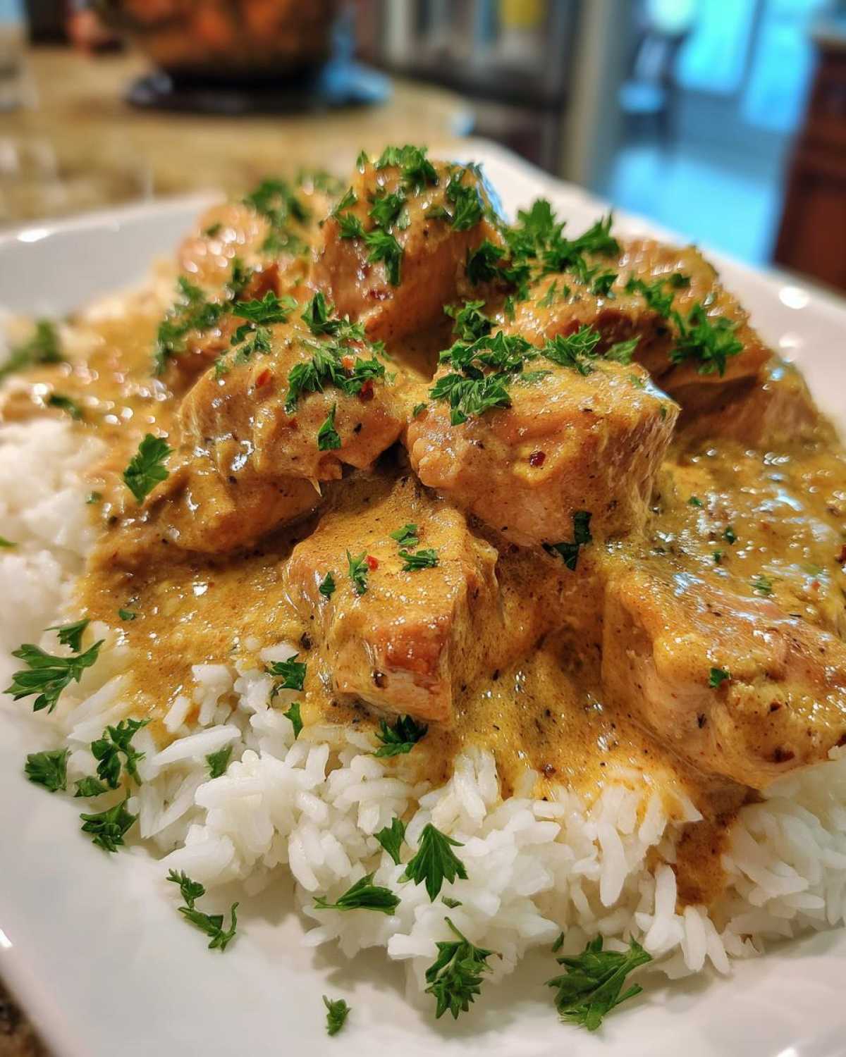 A plate of creamy smothered chicken and rice, garnished with parsley, ready to eat.