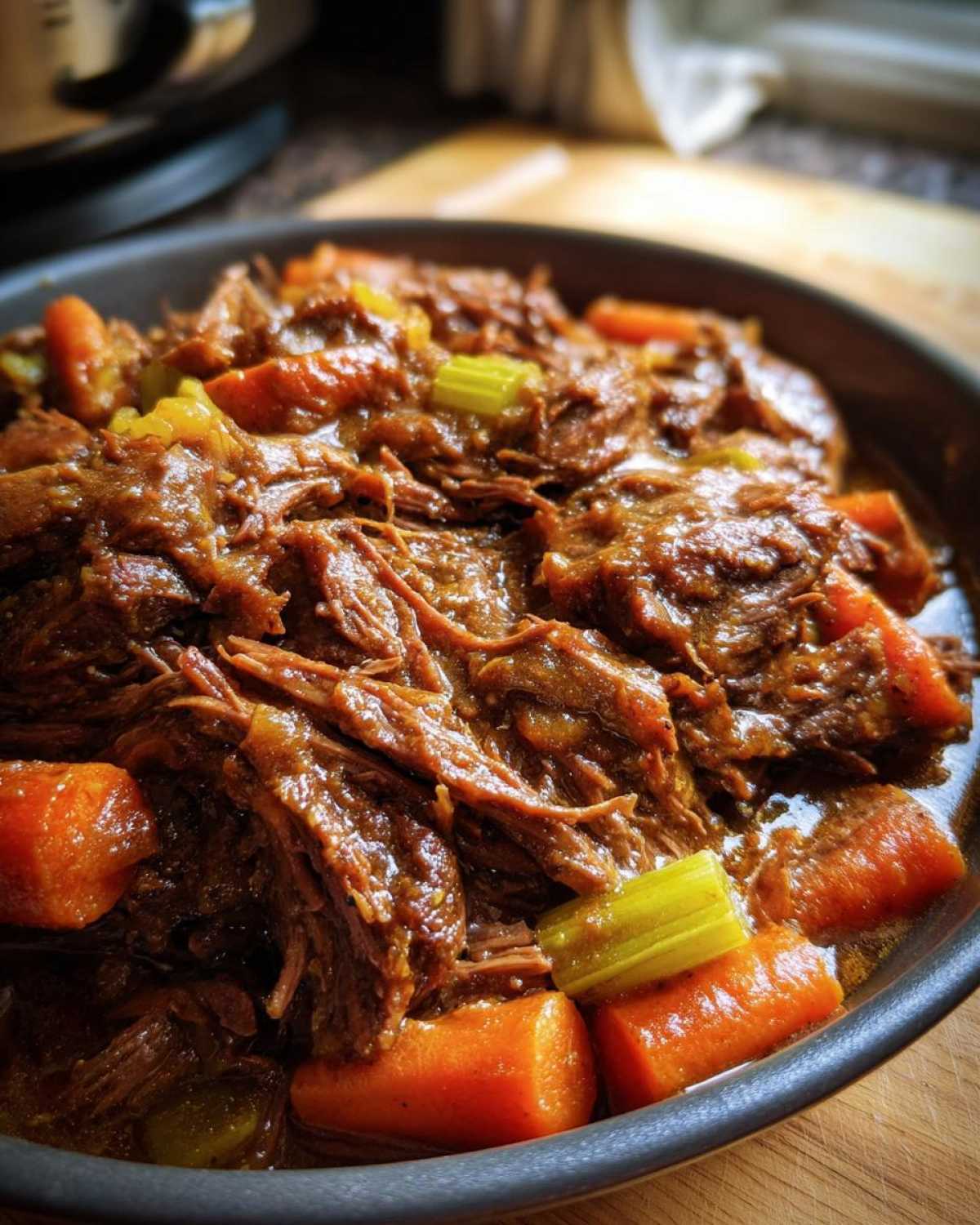 Close-up of a flavorful crockpot pot roast with carrots and celery, ready to serve.