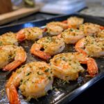 Close-up of Garlic Parmesan baked shrimp on a baking sheet, showcasing the golden-brown crust and fresh herbs.