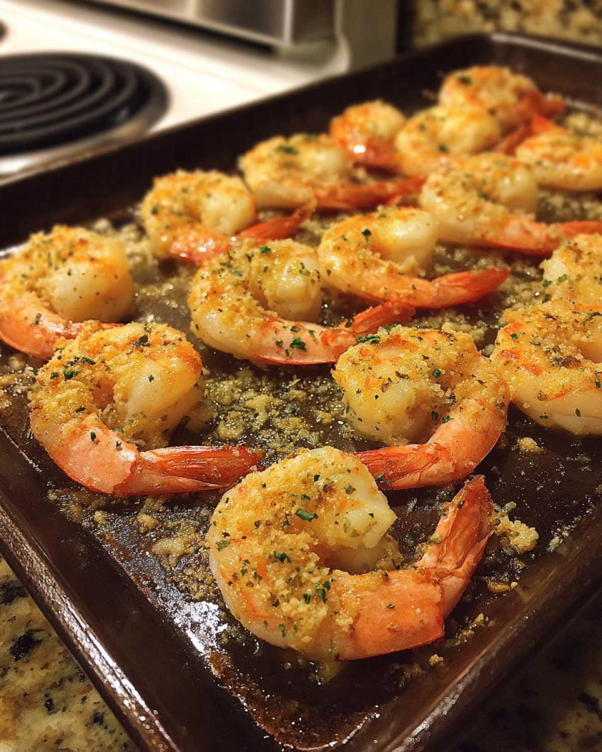 Close-up of Garlic Parmesan baked shrimp on a baking sheet, sprinkled with herbs.