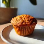 A single healthy pumpkin muffin on a plate, showcasing its texture and warm color.
