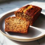 A slice of freshly baked high protein banana bread on a plate, showing its moist texture.