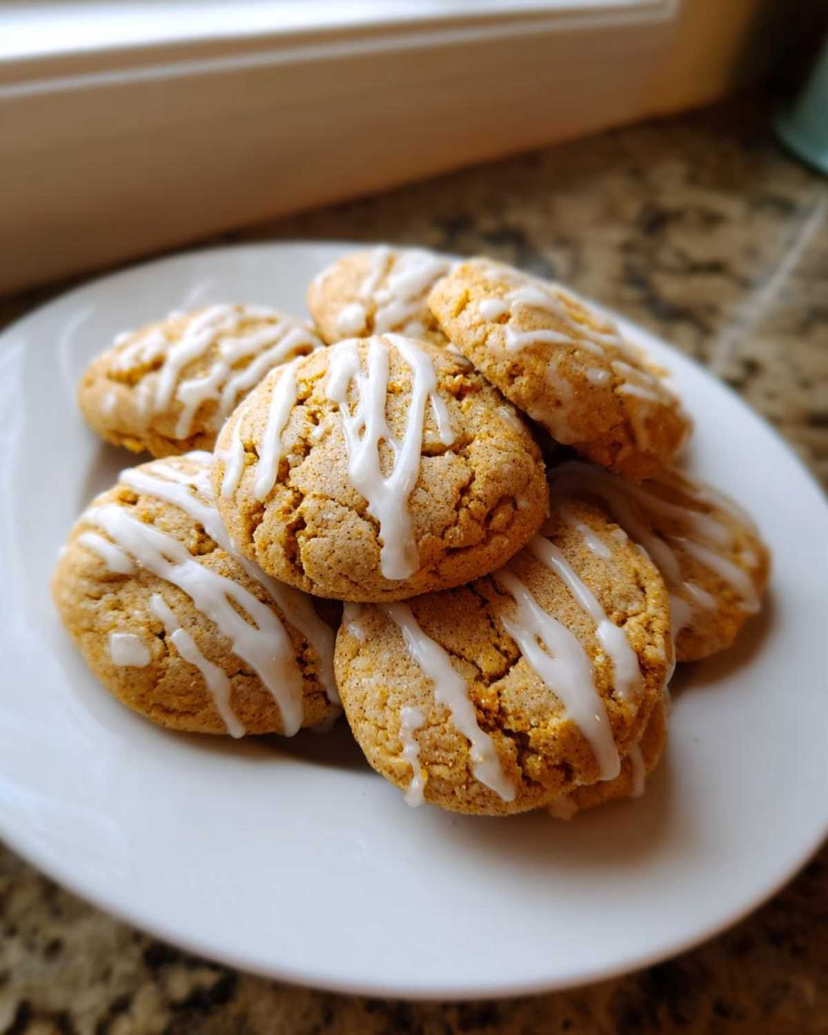 Pile of iced chai cookies on a white plate, ready to eat. Perfect for a quick 10-minute bake.