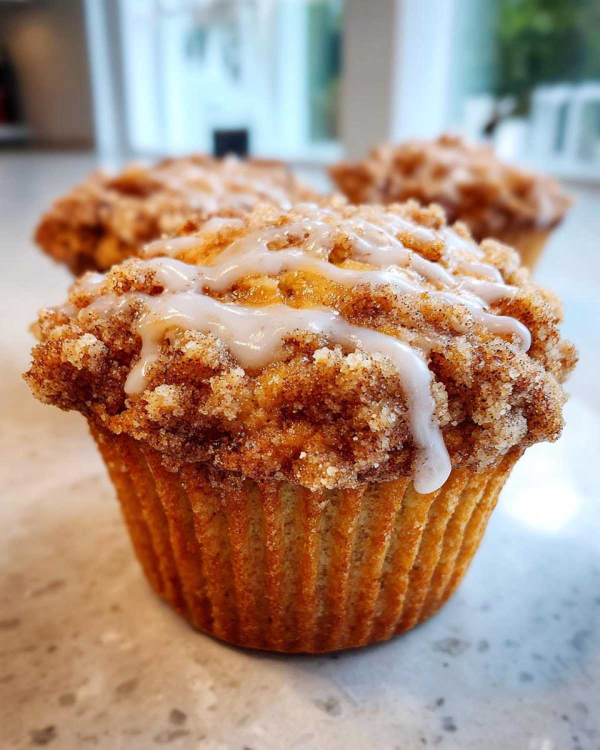 Close-up of iced coffee cake muffins with a crumb topping, showcasing their texture and glaze.