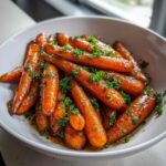 A bowl filled with delicious maple glazed carrots, garnished with fresh parsley.