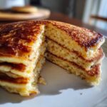 A stack of fluffy Protein Pancake Bowls, with a piece cut out to show the texture.