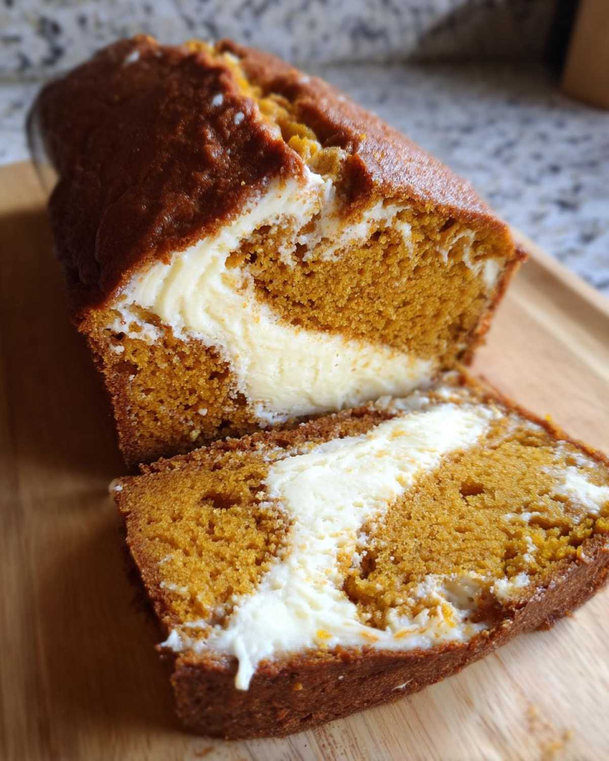 A sliced loaf of pumpkin cream cheese bread showing the swirl of cream cheese filling.