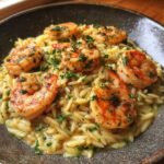A bowl of shrimp orzo in lemon garlic sauce, garnished with fresh parsley.