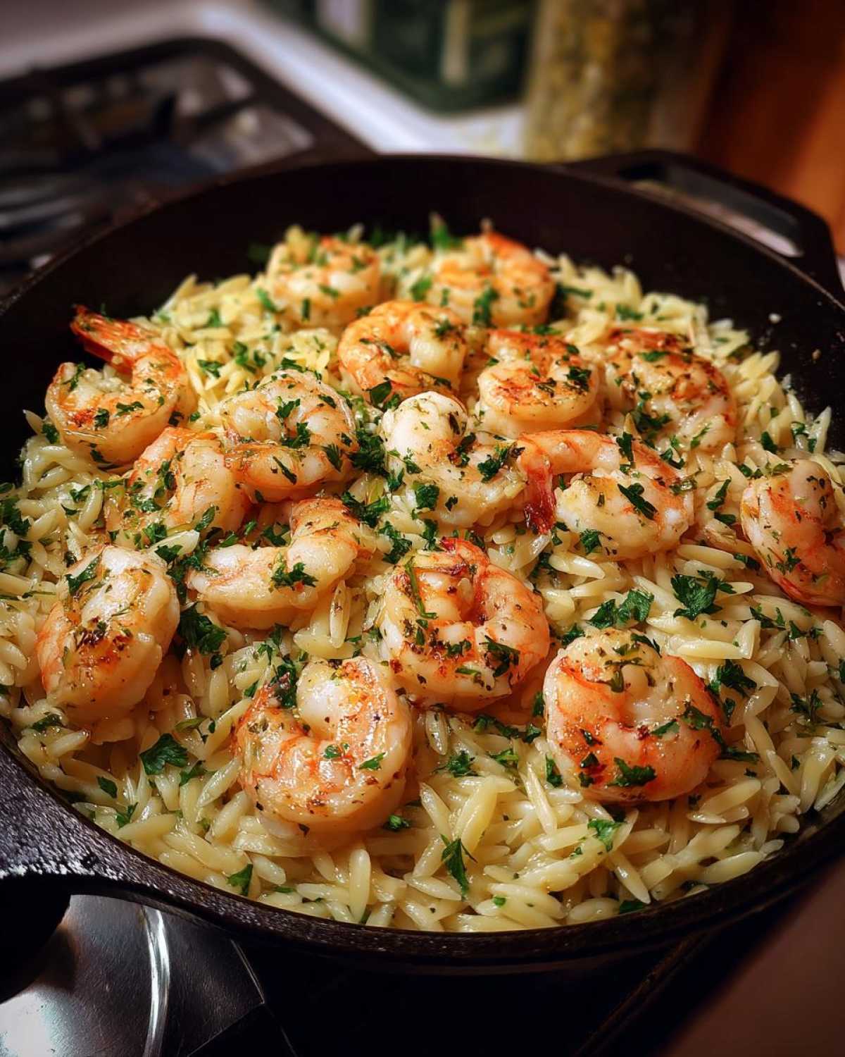 Pan of shrimp orzo in lemon garlic sauce, garnished with fresh parsley.