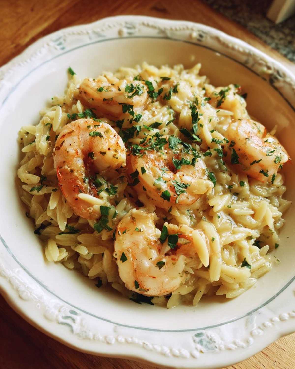 Bowl of shrimp orzo in lemon garlic sauce, garnished with fresh parsley.