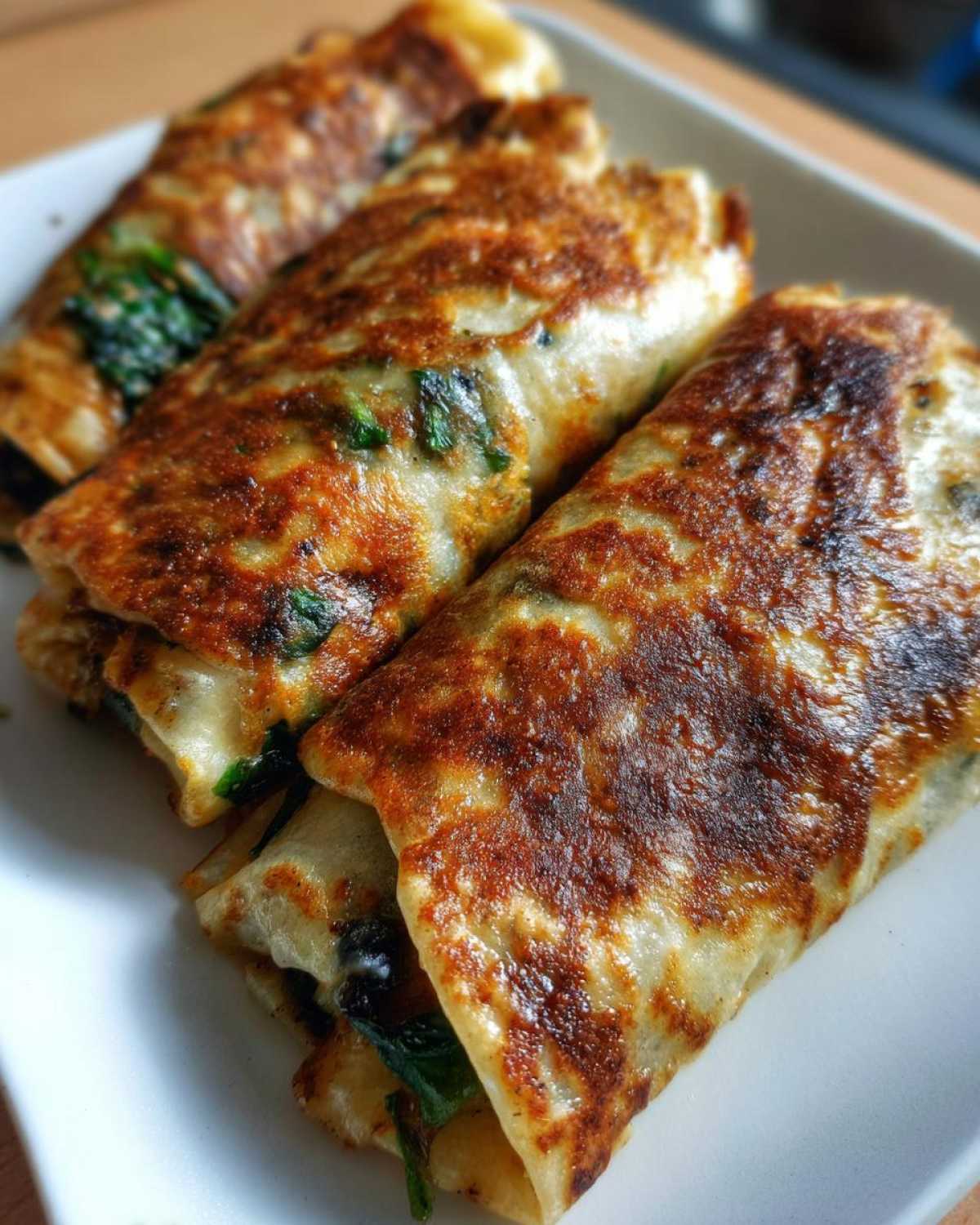 Three Spinach Black Bean Folded Wraps on a white plate, showcasing the golden-brown exterior.