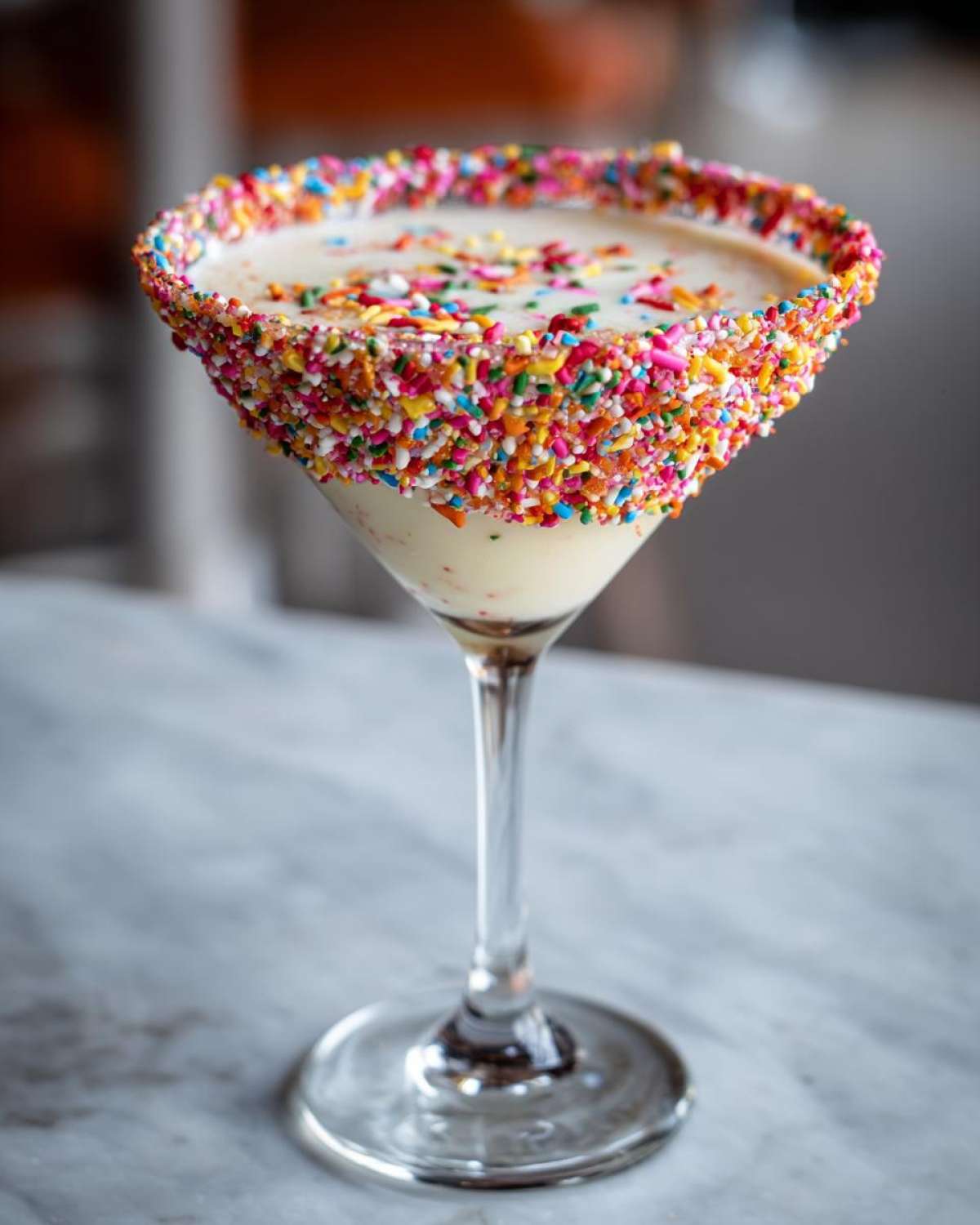 A sugar cookie martini in a glass rimmed with colorful sprinkles, perfect for a joyful celebration.