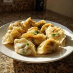 A plate filled with delicious, golden-brown Traditional Chinese Dumplings, garnished with fresh green herbs.