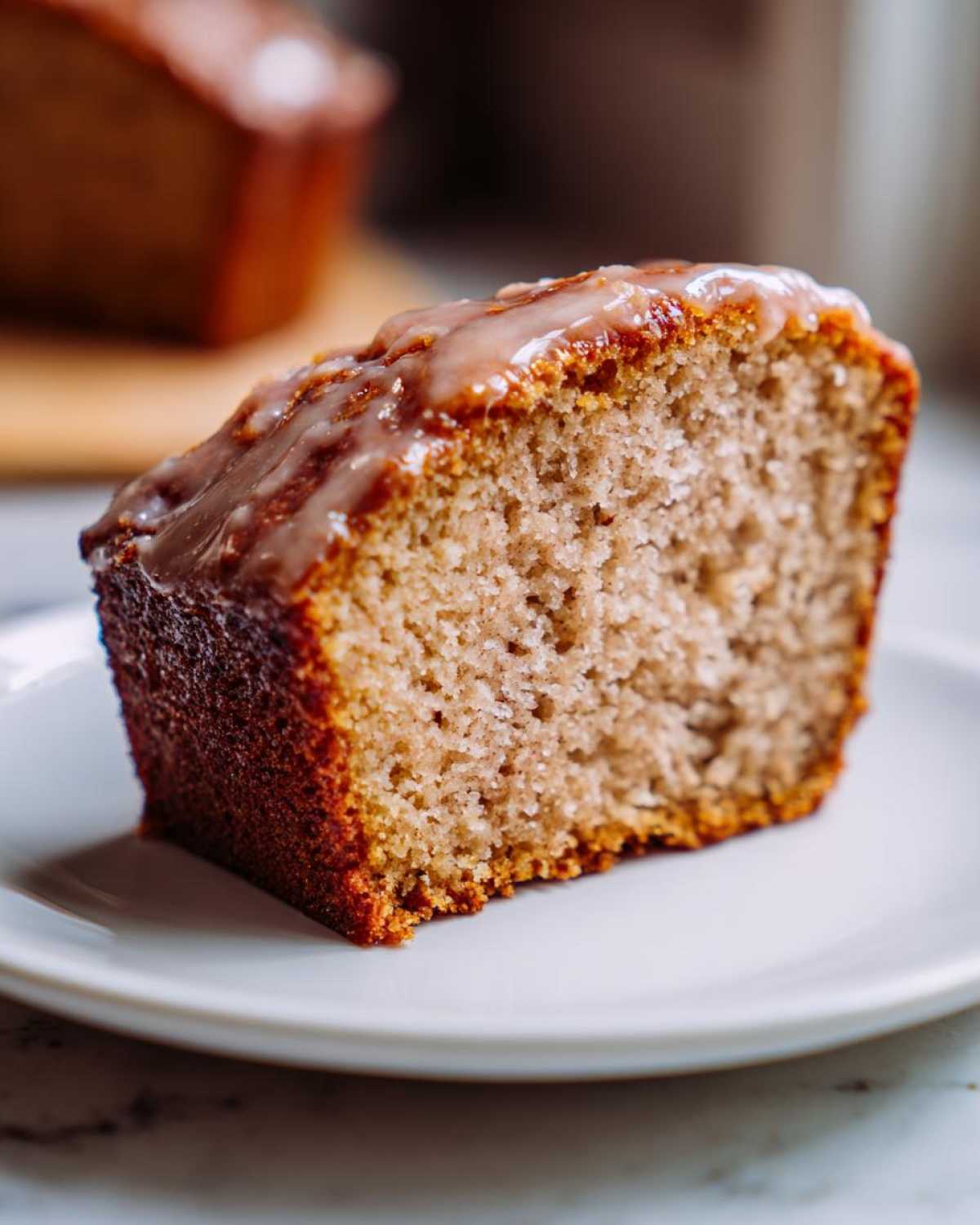 A delicious slice of Amish applesauce cake with a sweet glaze, served on a white plate.