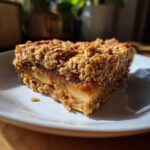 A slice of apple cinnamon cottage cheese bake with a golden oat topping on a white plate.