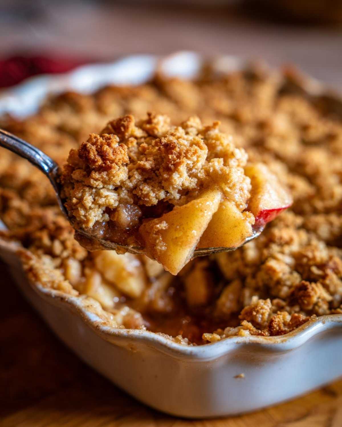 A spoonful of warm apple crisp with oats, showcasing the apple filling and golden oat topping.