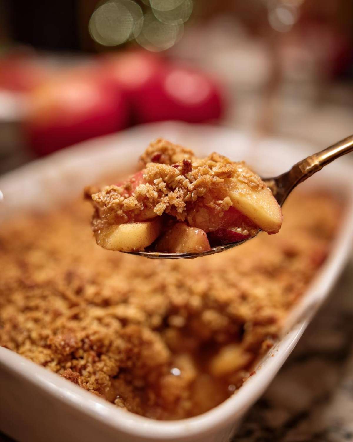 A spoonful of warm apple crisp with oats, showing the apple filling and crispy oat topping.