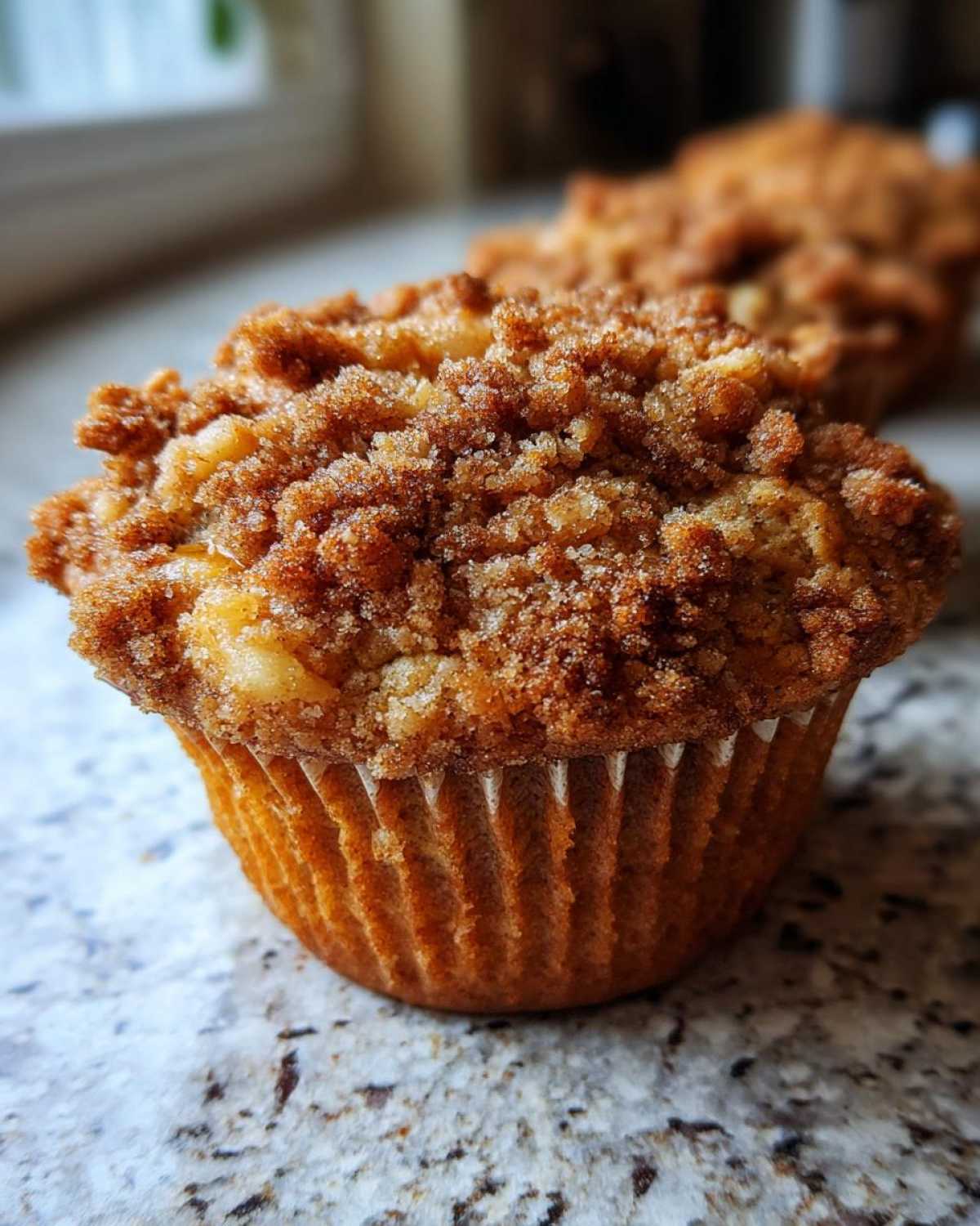 A close-up shot of an apple oatmeal muffin featuring a delicious crumble topping.