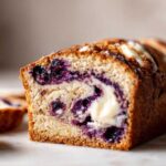 A close-up view of a slice of blueberry cream cheese bread, showcasing the blueberries and cream cheese swirl.