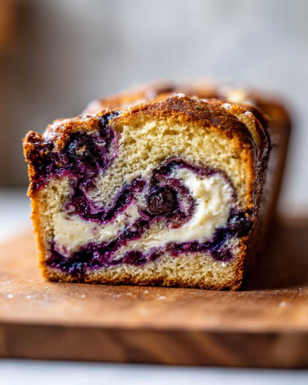 Close-up of a slice of blueberry cream cheese bread, showcasing the swirl of blueberries and cream cheese filling.