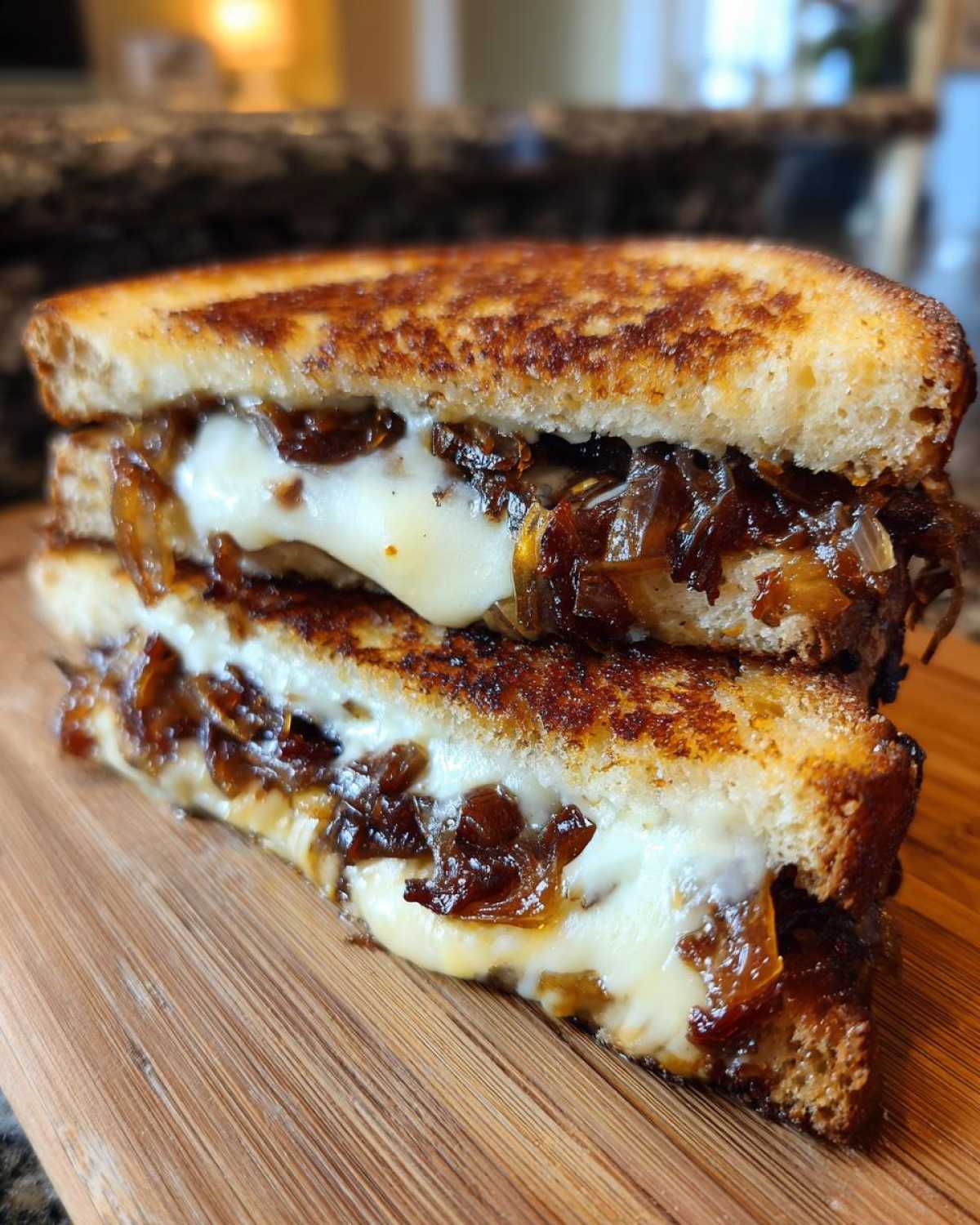 Delicious caramelized onion grilled cheese sandwich, stacked on a wooden board. Cheese is melted and onions are caramelized.